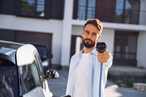 Symbolbild: Mann mit Ladekabel für Elektroauto